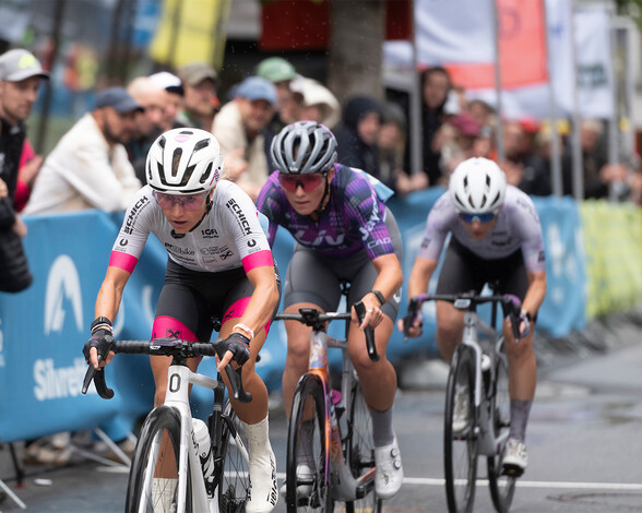 Drei Rennradfahrerinnen rasen in der Finalen Runde des Kriteriums durch die Fußgängerzone St. Antons.