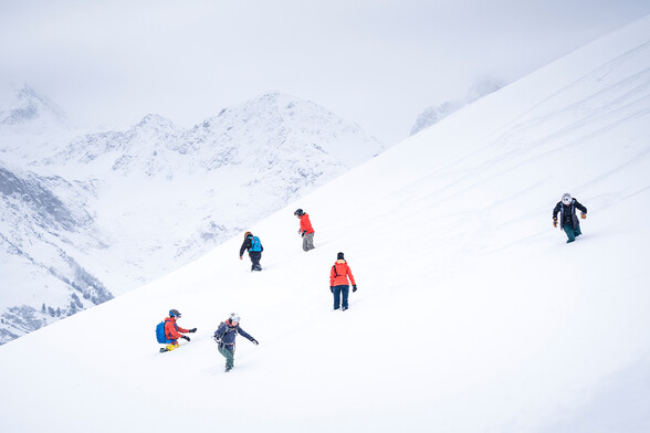 Winter sports enthusiasts practise probing during an avalanche safety camp in the snow-covered mountains.