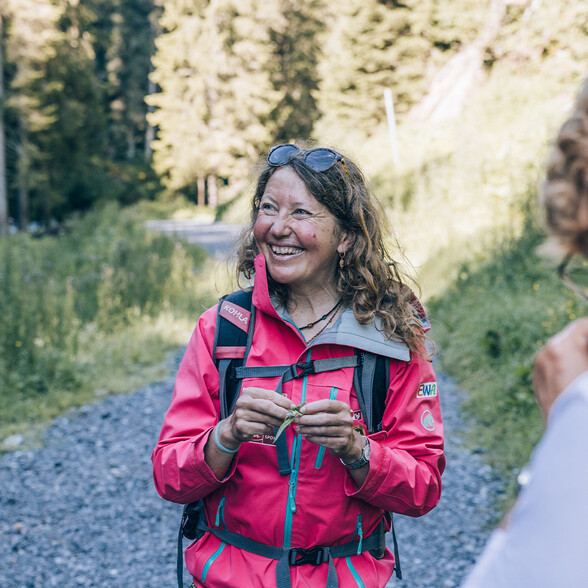 Silke Unseld in hiking gear, showing off a local plant.
