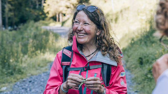 Silke Unseld in Wanderausrüstung, zeigt gerade eine lokale Pflanze her.