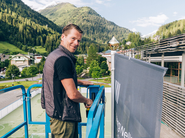 Allan Jensen beim Fahnenaustauch auf einem Steiger vor der Arlberg WellCom Halle.