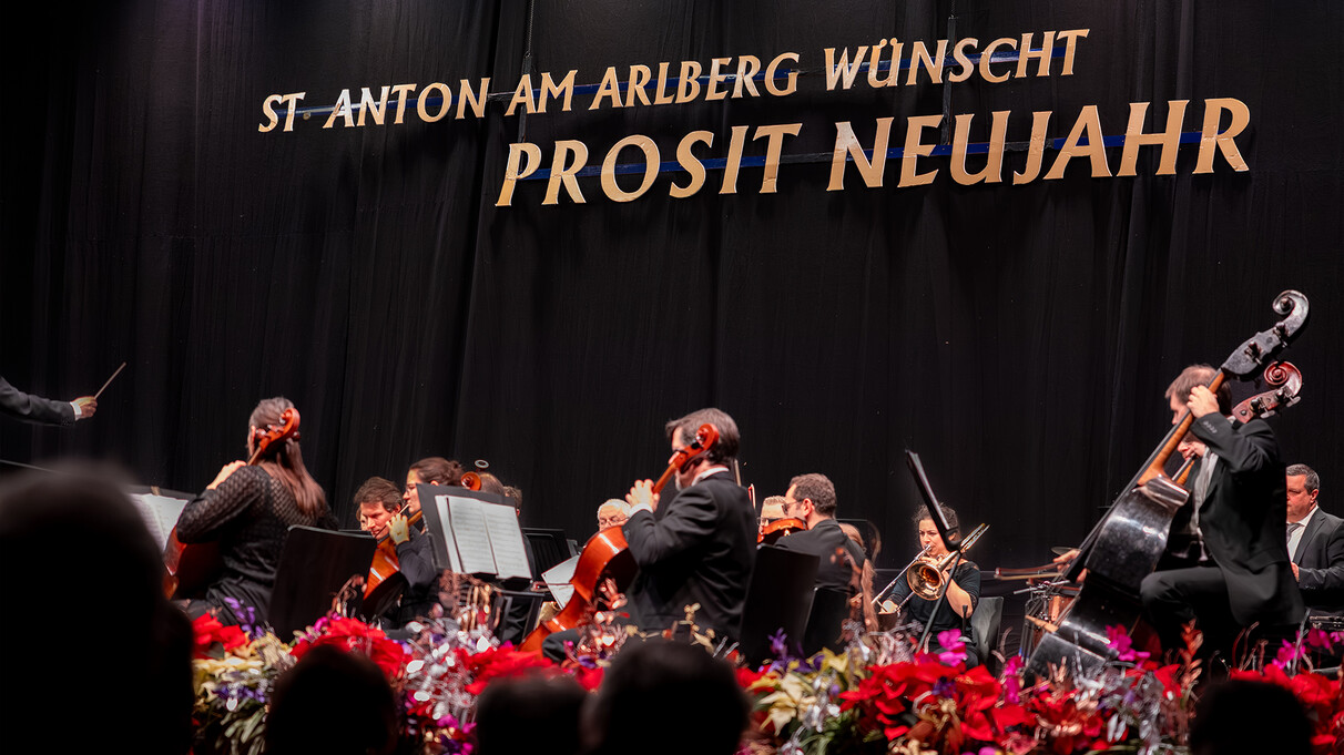 The Johann Strauss Ensemble plays classical music with woodwind and string instruments, the musicians are dressed in chic evening wear and stand on a wooden stage in a harmoniously lit hall.