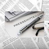 Ein Kugelschreiber liegt auf einem Stapel mit dem Titel „Pressemitteilung“.