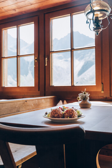 Dumplings on a table with a view through a window of the Darmstadt Hut of rocky mountains
