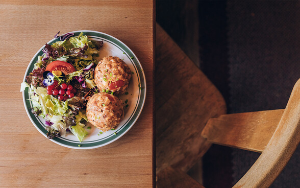 Tomaten-Mozzarella-Knödel mit Salat Tomaten-Mozzarella-Knödel mit Salat auf einem Tisch. Im Bild ist als text vermerkt, dass die Knödel auch optisch einiges hergeben.