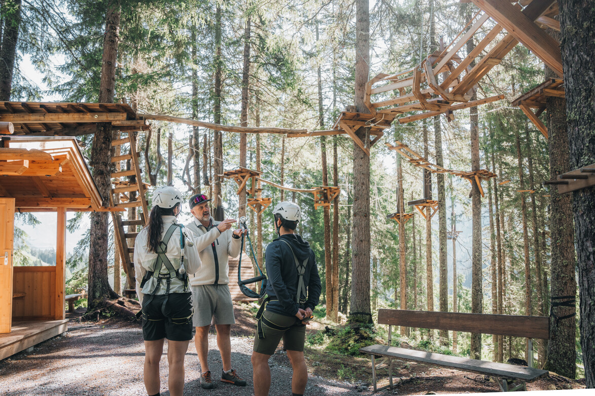 Sicherheitseinweisung im Waldseilgarten Zwei Personen erhalten vor dem Start eine Sicherheitseinweisung im Waldseilgarten von einem Guide.