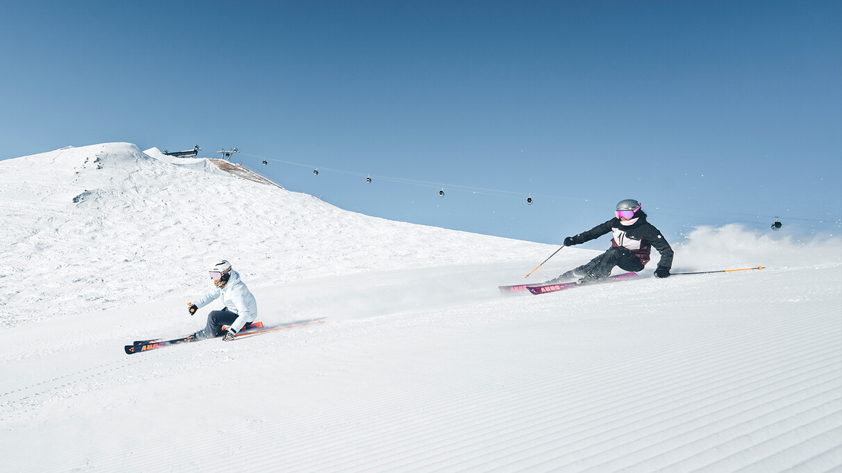 Two female skiers carving down a slope in St. Anton