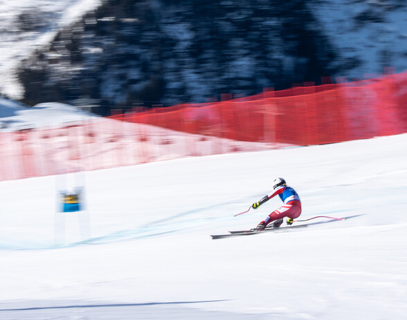 Skirennläufer in roter Hose und blau-weiß-rotem Oberteil fährt auf einer schneebedeckten Piste