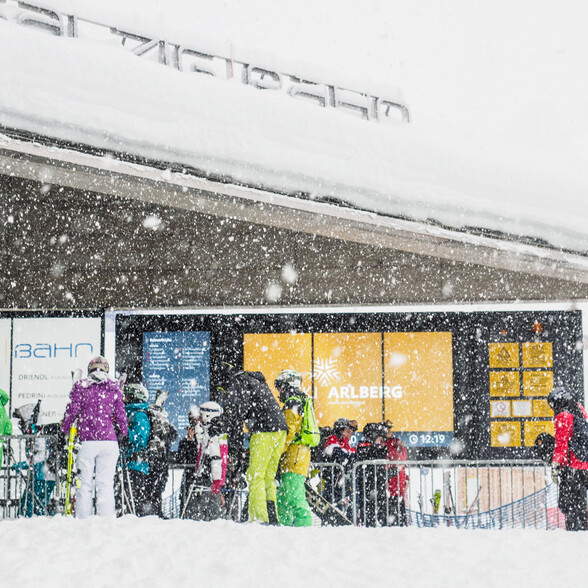 Group of people in ski gear standing outside a building in heavy snowfall
