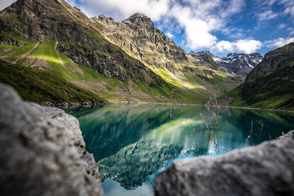 The turquoise-blue Kartell Reservoir nestled among the surrounding mountain peaks