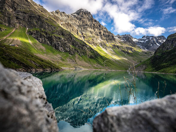 The turquoise-blue Kartell Reservoir nestled among the surrounding mountain peaks