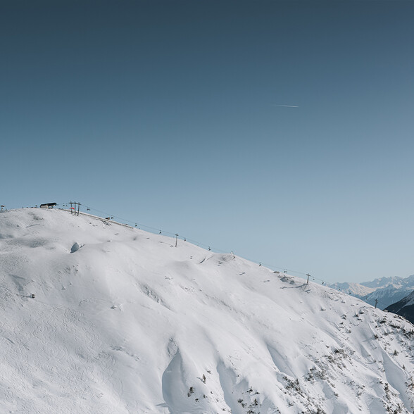 Schneebedeckter Berg mit Skiliften und Sesselliften unter klarem Himmel