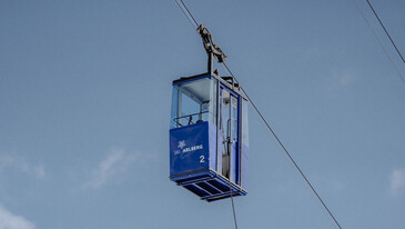 Arlberger Bergbahnen Blue cable car cabin labeled 'Ski Arlberg 2' suspended on cables against a clear sky