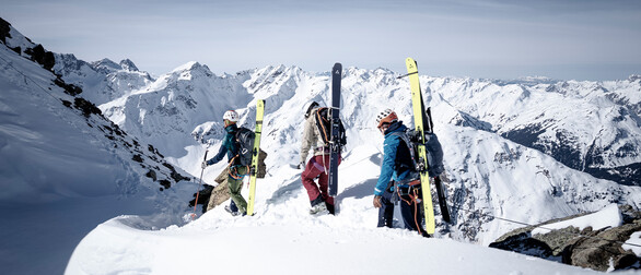 Experience Shop Tre alpinisti mentre scalano una cresta in inverno