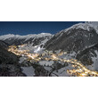 St. Anton bei Nacht mit beleuchteten Häusern und verschneiten Bergen. / St. Anton at night with illuminated houses and snowy mountains.