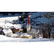 Die verschneite Pettneu Kirche im Fokus einer Aufnahme von etwas höher am Berg /  The snow-covered Pettneu church in the focus of a shot from a little higher up the mountain