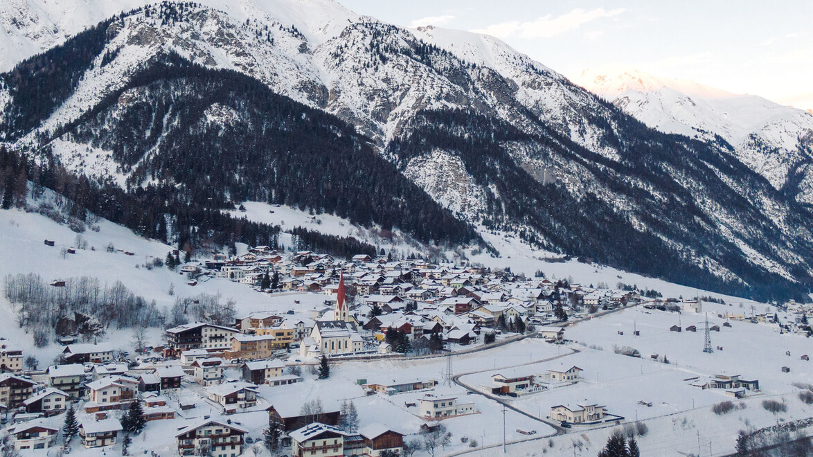 Drohnenaufnahme vom verschneiten Dorf Pettneu im Winter / Drone shot of the snow-covered village of Pettneu in winter