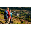 Zwei Wanderer auf einem Pfad mit Blick auf St. Christoph und umliegende Almwiesen. / Two hikers on a trail overlooking St. Christoph and surrounding alpine pastures.