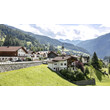 Blick auf das Dorf Flirsch mit Wiesen und Bergen bei Sonne. / View of Flirsch village with meadows and mountains in summer sun.