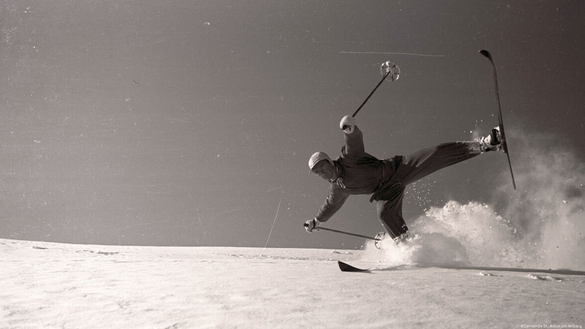 Skifahrer in der Luft bei Kunstsprung, Schnee wirbelt auf. / Skier mid-air performing trick jump, snow swirling around.