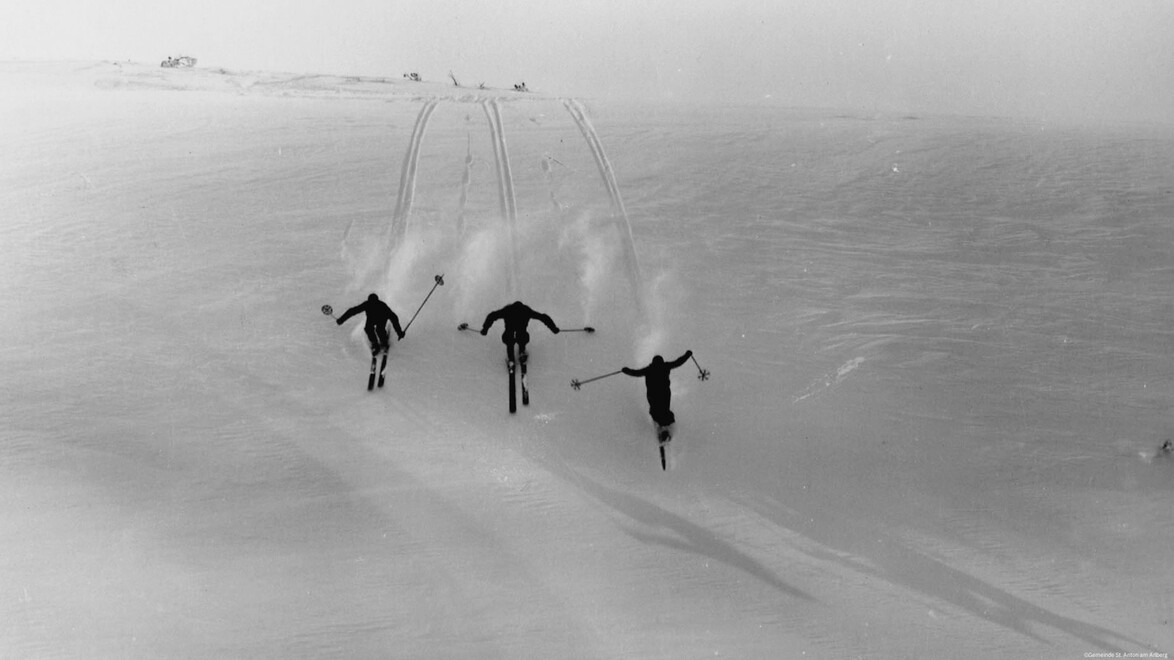 Drei Männer fahren parallel durch frischen Pulverschnee – dynamisch und synchron. / Three men ski in parallel through fresh powder snow – dynamic and synchronized.