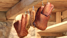 Various pieces of bacon hang to dry under the wooden ceiling of the traditional Nessler Thaja near St. Anton am Arlberg.