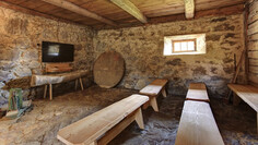 Rustic projection room with stone floor, wooden benches and information monitor in the old Nessler Thaja
