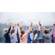 Menschen heben gemeinsam die Arme in der Natur bei einer Yogaübung. — People raise their arms together during an outdoor yoga session in nature.
