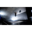 Ein Freestyler macht einen Rückwärtssalto, umgeben von Licht und Nebel auf einer Indoor-Fläche. / A freestyler performs a backflip surrounded by light and fog on an indoor surface.