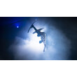 Ein Freestyle-Springer zeigt einen Trick mit Ski inmitten von Shownebel und blauem Licht. / A freestyle jumper performs a trick on skis amid show fog and blue lighting.