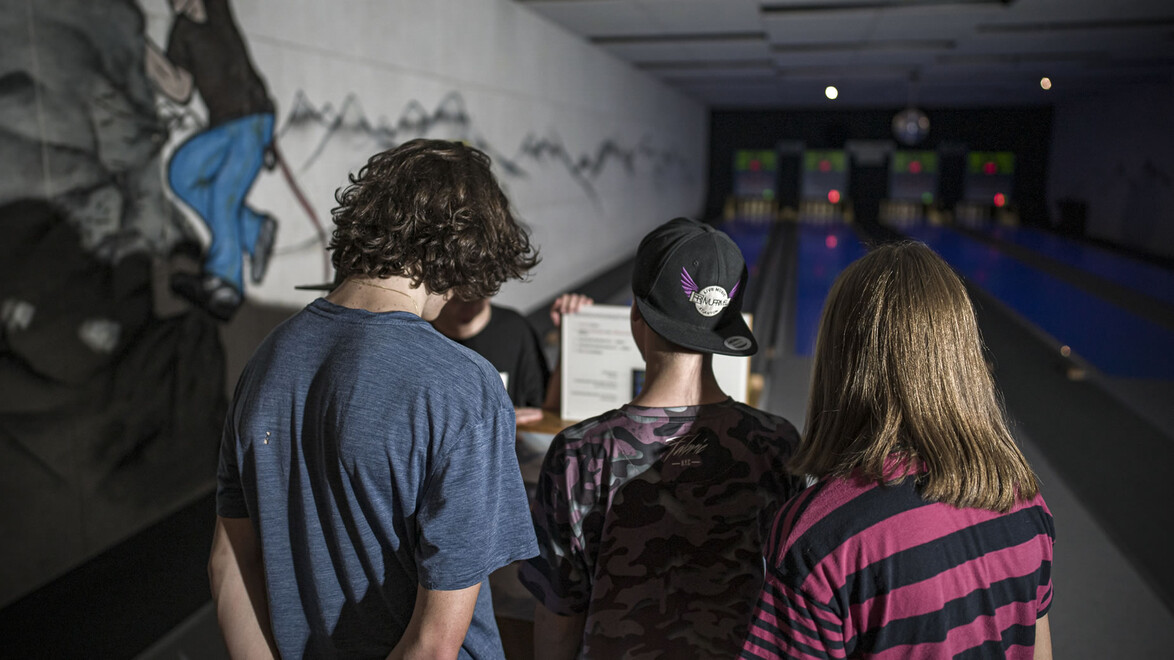 Drei Jugendliche von hinten, Blick auf Kegelbahn und Punkteliste / Three teenagers seen from behind, looking at scoreboard and bowling lane