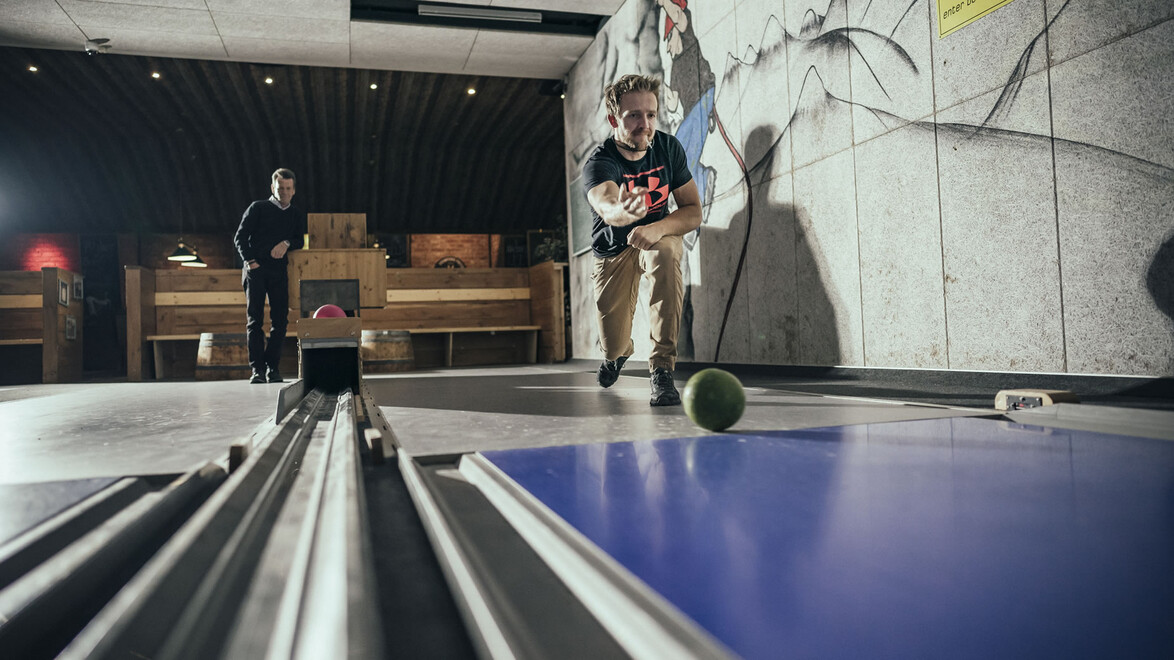 Zwei Personen beim Kegeln in einer modernen Halle mit Holzdekor / Two people bowling in a modern hall with wooden decor
