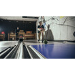 Zwei Personen beim Kegeln in einer modernen Halle mit Holzdekor / Two people bowling in a modern hall with wooden decor