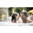 Ein Paar entspannt sich gemeinsam im sprudelnden Außen-Whirlpool / A couple relaxes together in the bubbling outdoor whirlpool