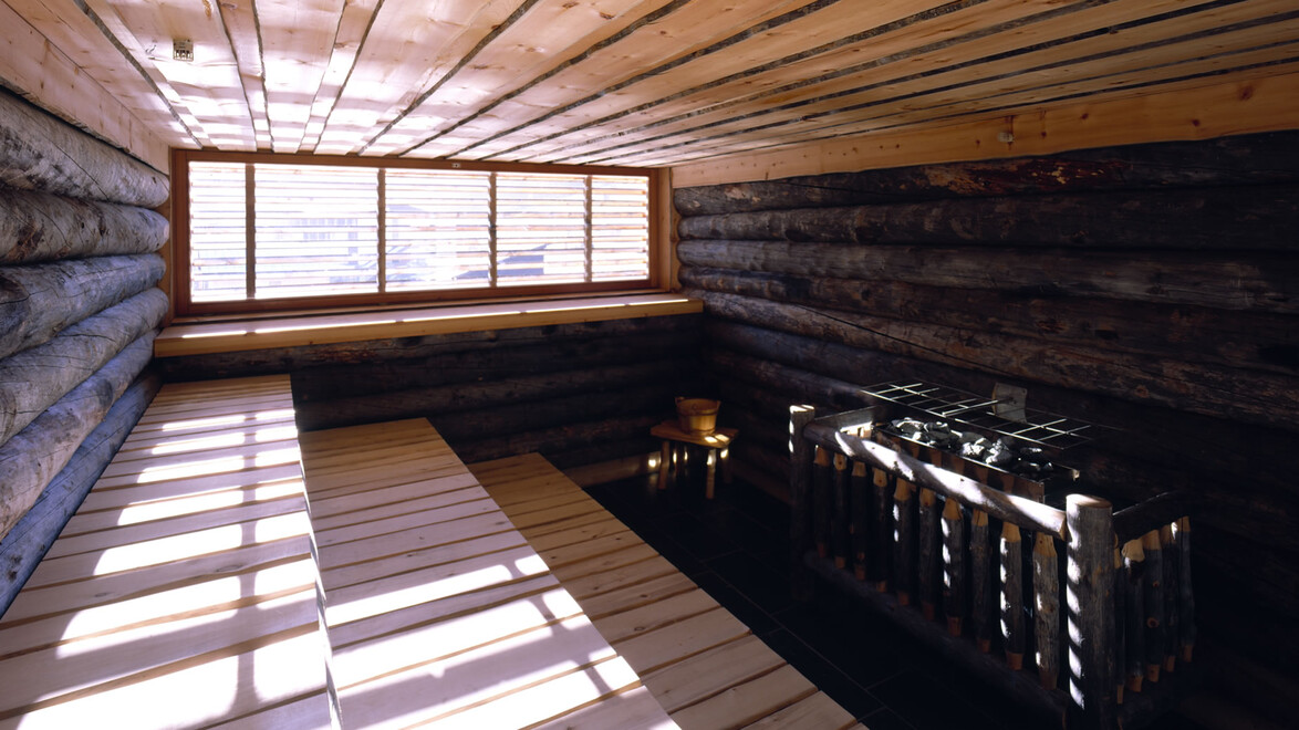 Traditionell gestalteter Saunaraum mit Holzverkleidung und Blick ins Freie / Traditional sauna room with wooden interior and outdoor view