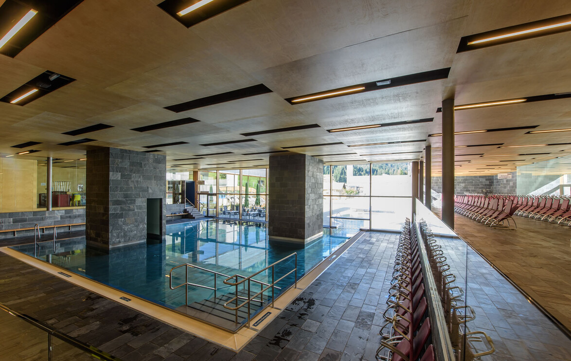Modernes Hallenbad mit mehreren Bahnen, Sitzreihen und Glasfassade / Modern indoor pool with multiple lanes, seating rows and glass façade