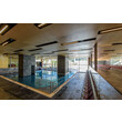 Modernes Hallenbad mit mehreren Bahnen, Sitzreihen und Glasfassade / Modern indoor pool with multiple lanes, seating rows and glass façade