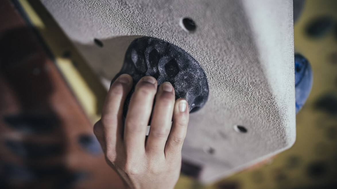 Nahaufnahme einer Hand beim Greifen eines Klettergriffs / Close-up of a hand gripping a climbing hold