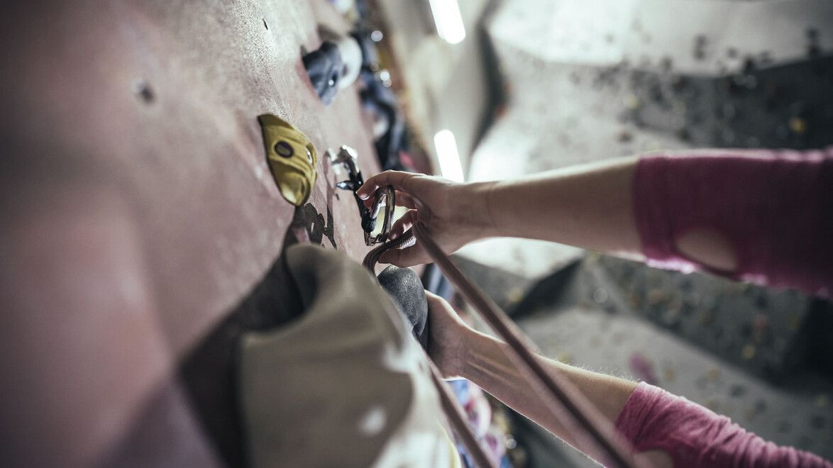 Nahaufnahme von Händen beim Clippen in einen Sicherungshaken / Close-up of hands clipping into a safety hook