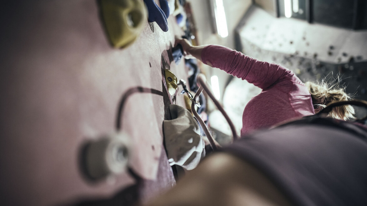 Kletterin in der Wand mit Sicherungskarabinern / Female climber on wall with safety carabiners