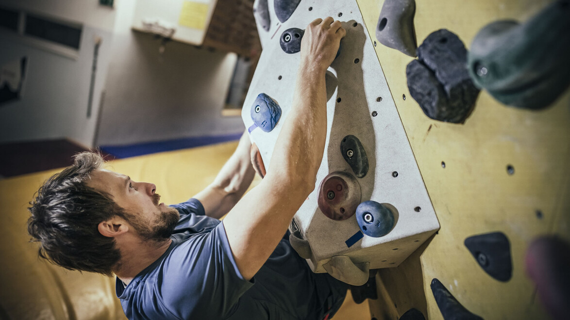 Kletterer mit Fokus auf Technik am Trainingsboard / Climber training technique on fingerboard