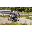 Gruppe von Radfahrer:innen wartet beim Pumptrack, eine Person fährt aktiv / Group of cyclists waiting at the pump track, one person riding actively