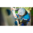 Person mit Helm und Gurt klettert konzentriert eine senkrechte Wand im Hochseilgarten / Person with helmet and harness climbs vertical wall in high ropes course