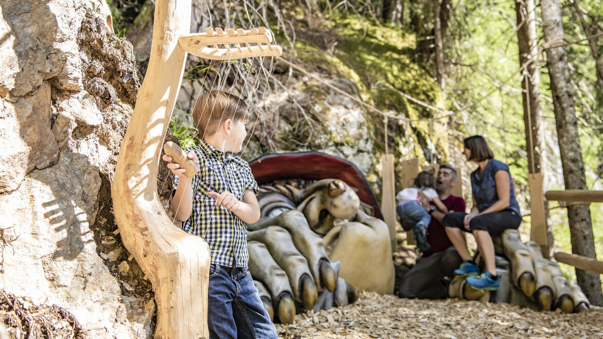 Holzskulpturen und Sitzbank im Wald, Kind beobachtet Szene / Wooden sculptures and bench in the forest, child observing the scene