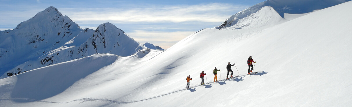 Group ascending untouched snow with steep alpine peaks in St. Anton in the background.