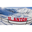 Rote Buchstaben mit „St. Anton“ stehen vor verschneiter Bergkulisse mit Sessellift im Hintergrund / Red “St. Anton” letters in front of a snowy mountain backdrop with a chairlift in the background