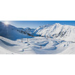 Panoramaaufnahme des Snowparks mit mehreren Schanzen und Rails, umgeben von verschneiten Bergen / Panoramic view of the snow park with jumps and rails, surrounded by snowy mountains