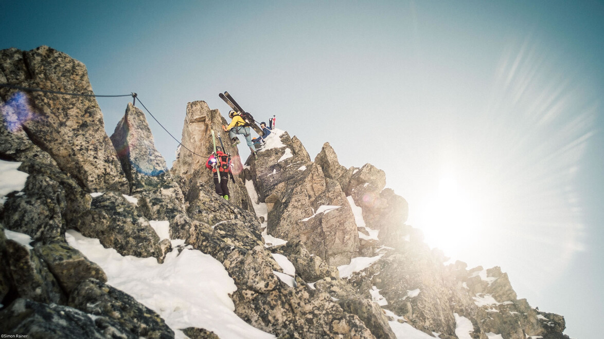 Skitourengeher durchqueren sonnige Gratpassage mit Schneefeldern / Ski tourers crossing sunny ridge section
