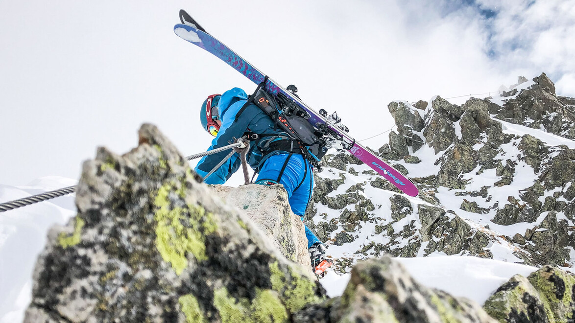 Skibergsteiger mit blauem Anzug auf steinigem Gratabschnitt / Ski mountaineer in blue suit on rocky ridge