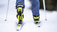 Nahaufnahme eines Langlaufschuhs in der Spur auf präparierter Schneeloipe.